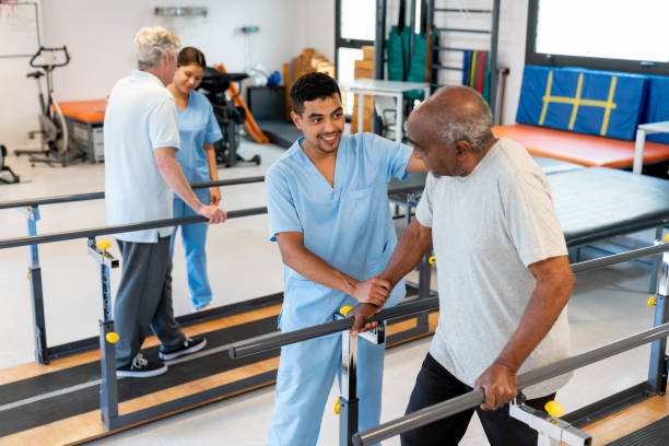 Physical therapist assisting a senior patient with gait training exercises on parallel bars in a physiotherapy clinic.