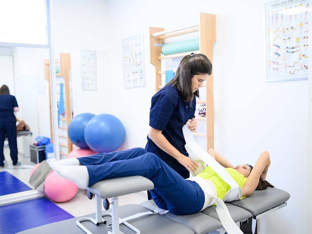 Physiotherapist using manual traction straps to treat spinal curvature and improve posture during a scoliosis rehabilitation session